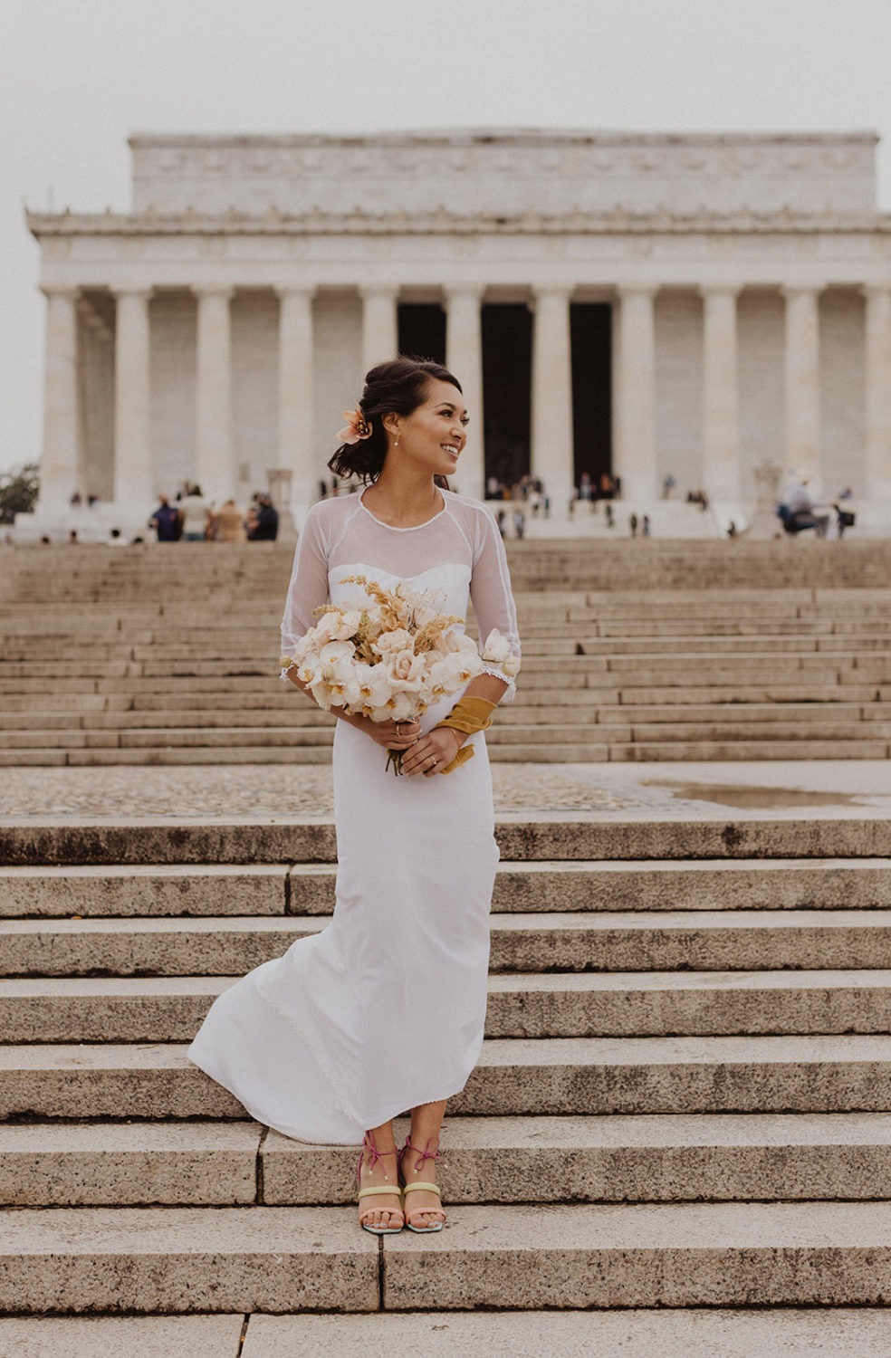 bride stands holding wedding bouquet at Lincoln Memorial