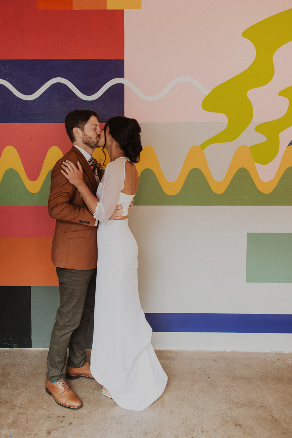 couple kisses in front of colorful wall at Culture House DC wedding venue
