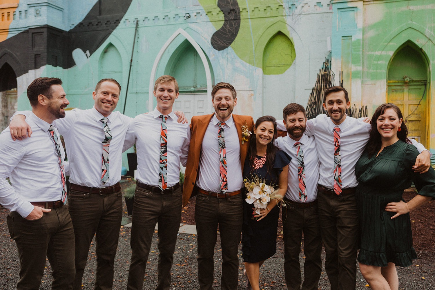 groom stands with wedding party wearing matching ties