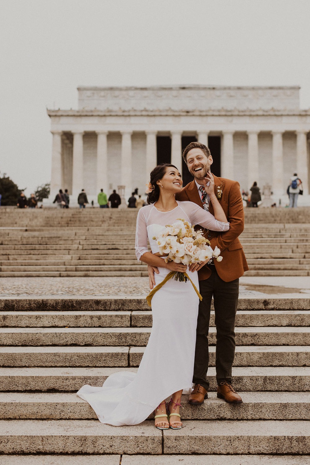 couple embraces standing in front of Lincoln Memorial