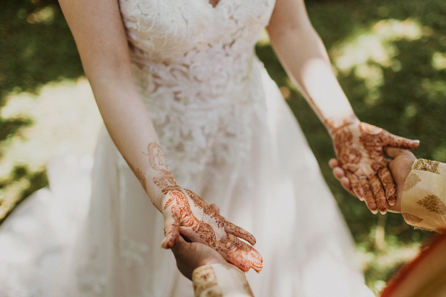 couple stands holding hands with henna on bride's arms and hands