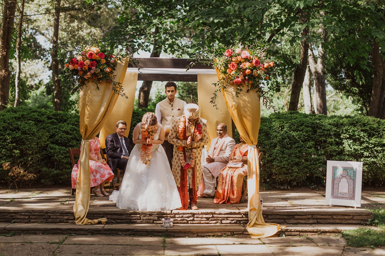 couple bows for a blessing during outdoor wedding ceremony