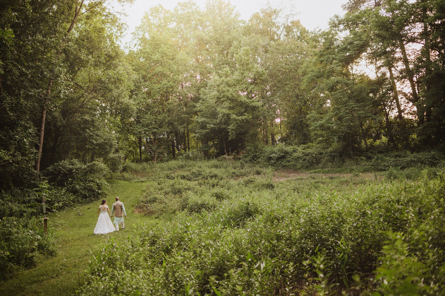 couple walks through the woods at outdoor maryland wedding