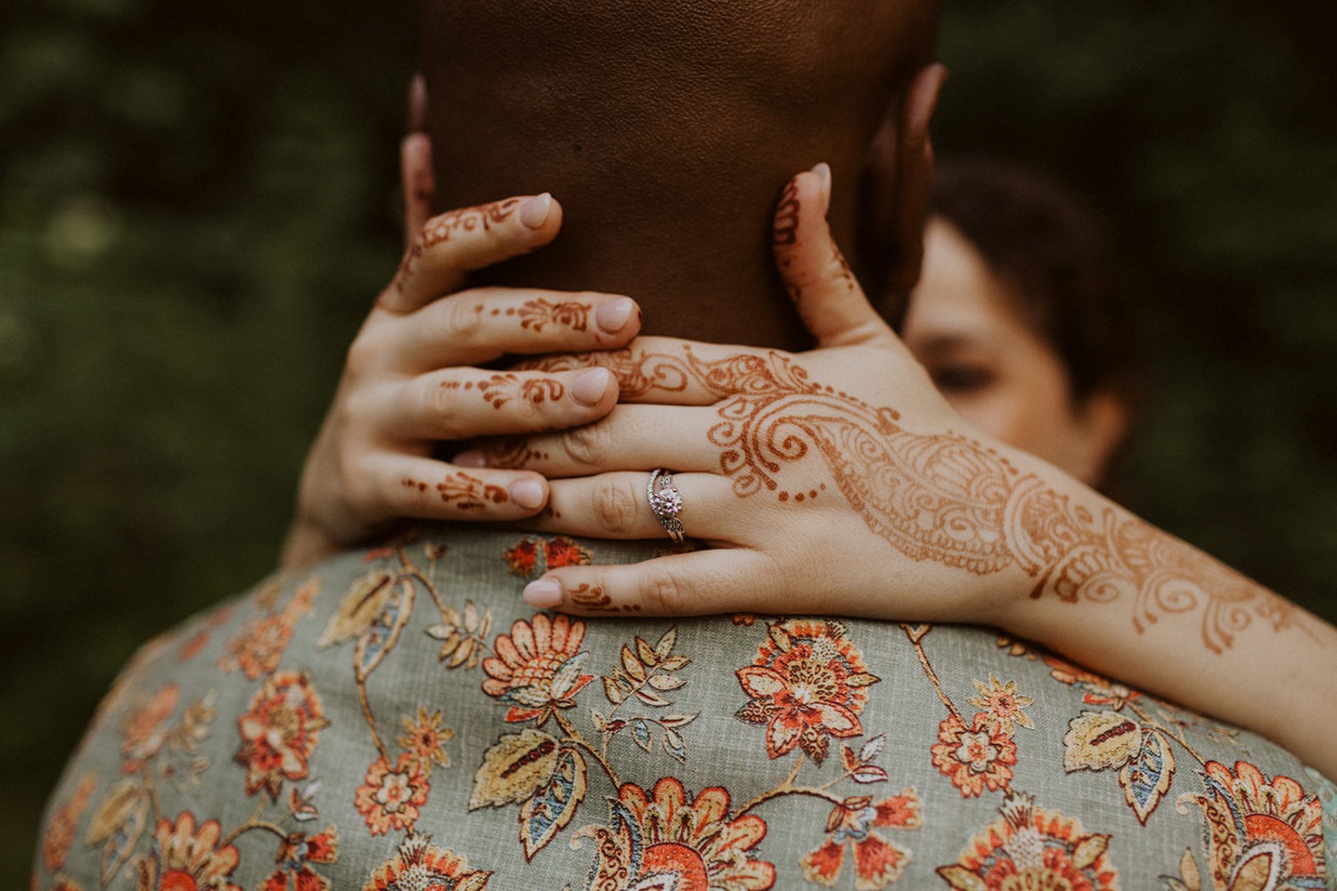 bride embraces groom with henna on her hands