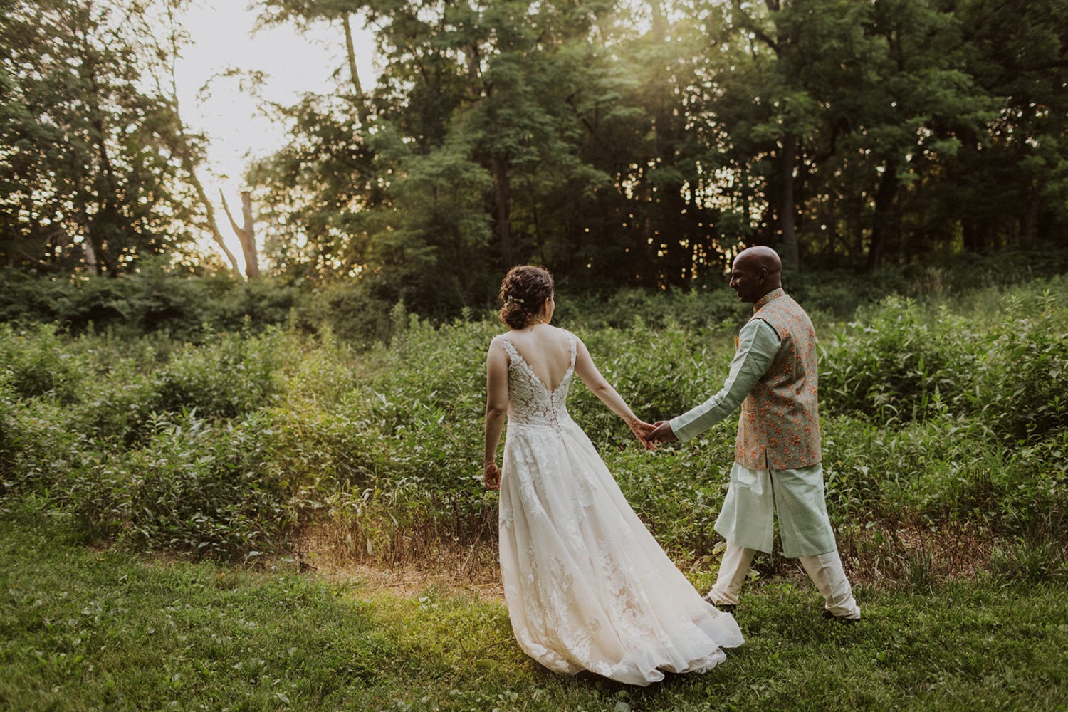 couple walks through green forest at outdoor maryland wedding