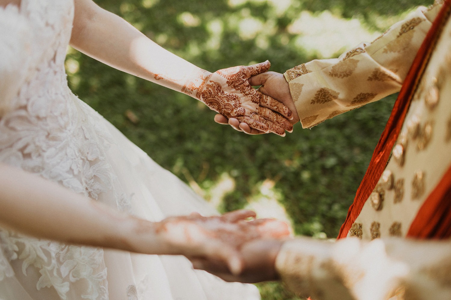 groom holds bride's hands with henna