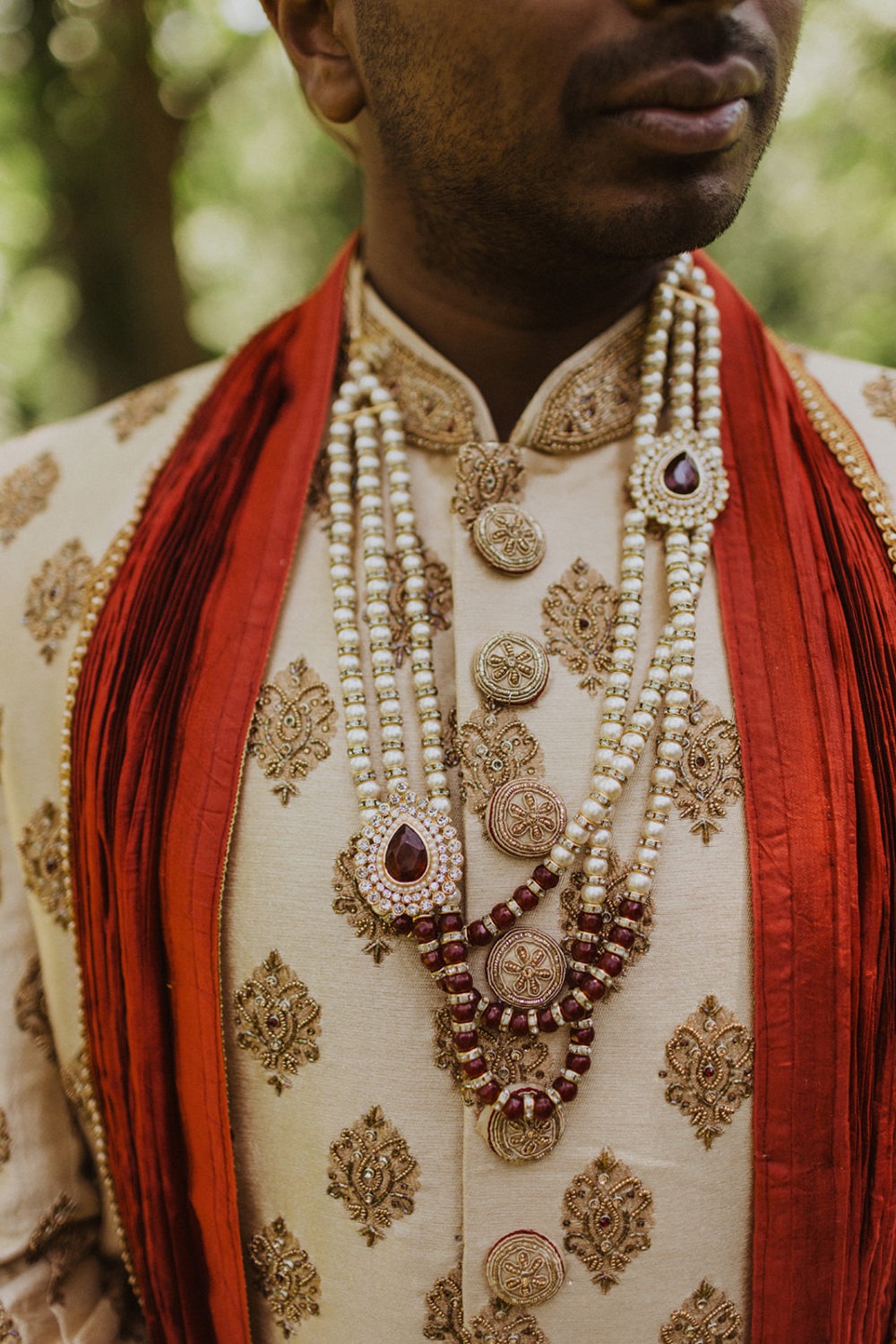 groom stands with jewelry on indian clothing