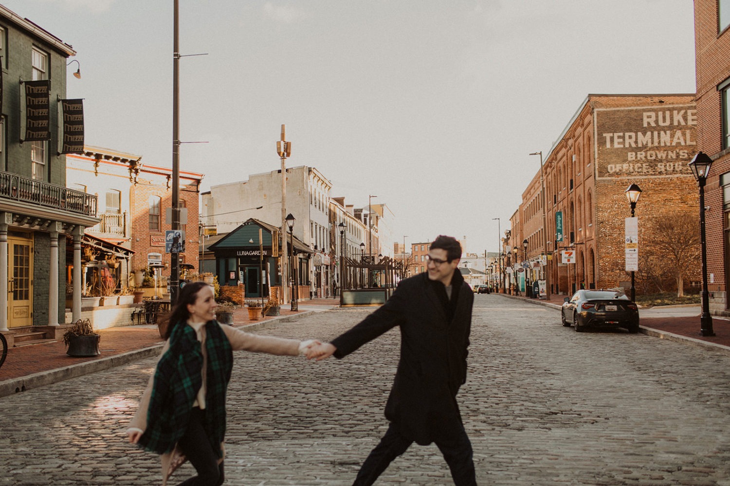 couple walks holding hands at Baltimore engagement photos in winter