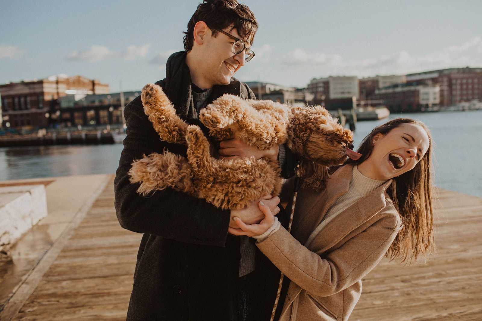 couple holds dog together at engagement photos in winter