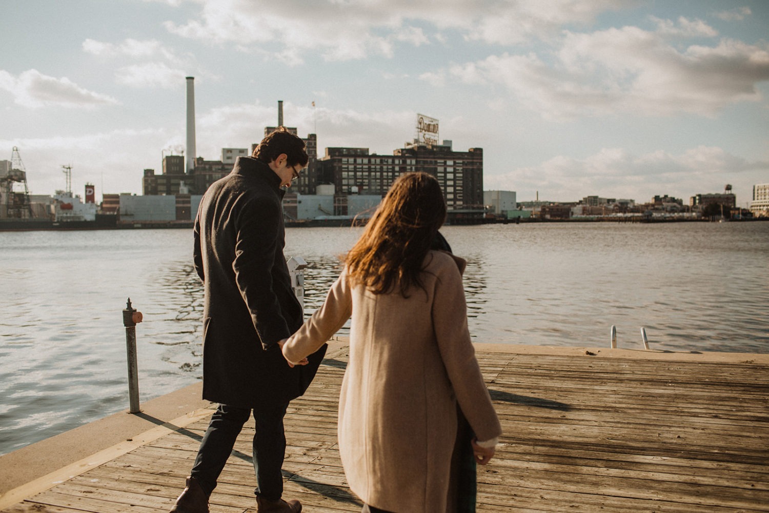 couple walks holding hands at Baltimore engagement photos in winter