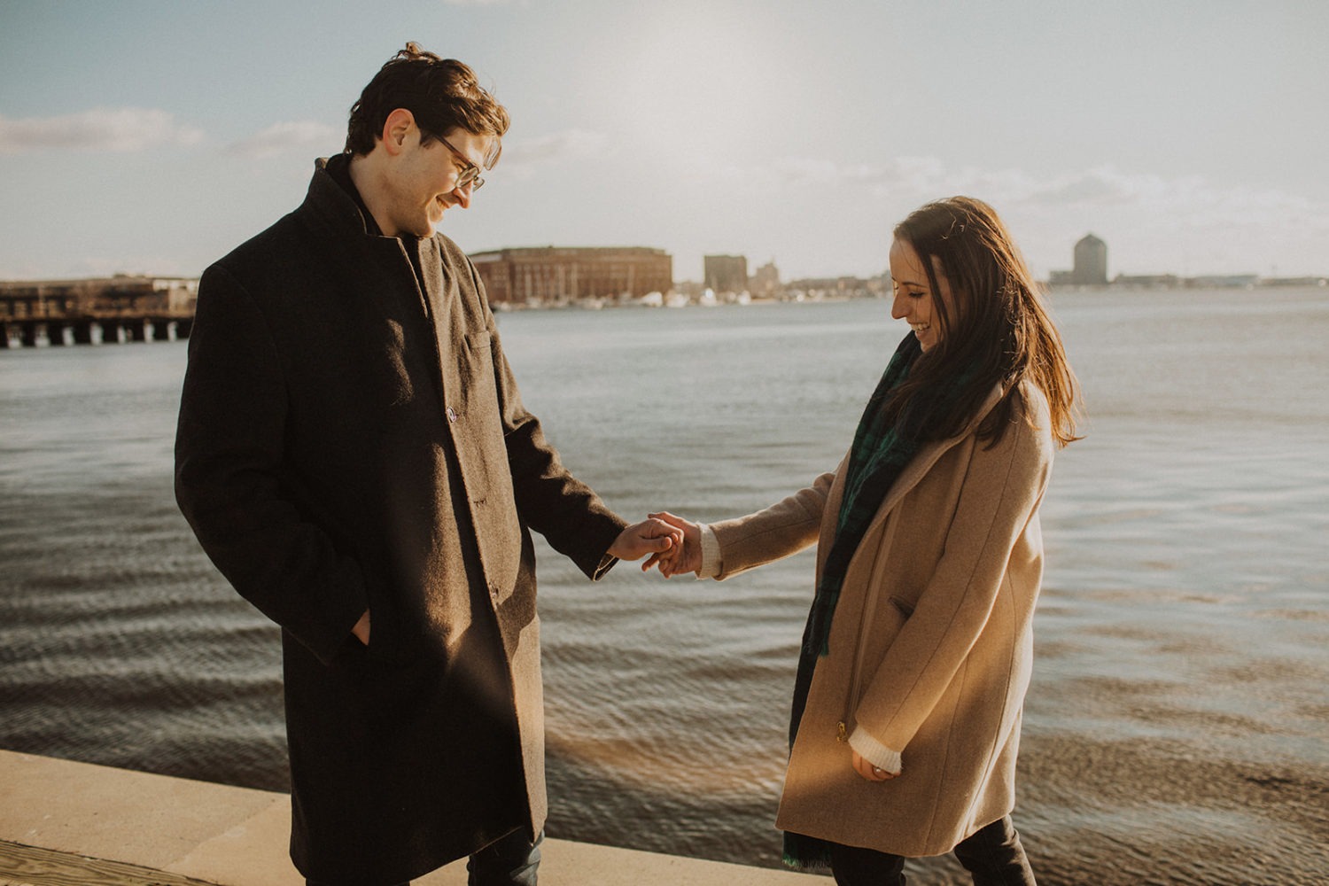 couple holds hands at Baltimore windy winter engagement session