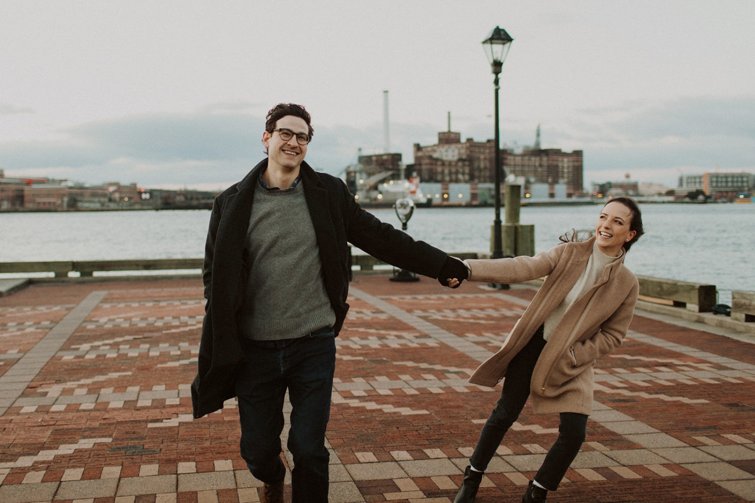 couple walks holding hands at Baltimore windy winter engagement session