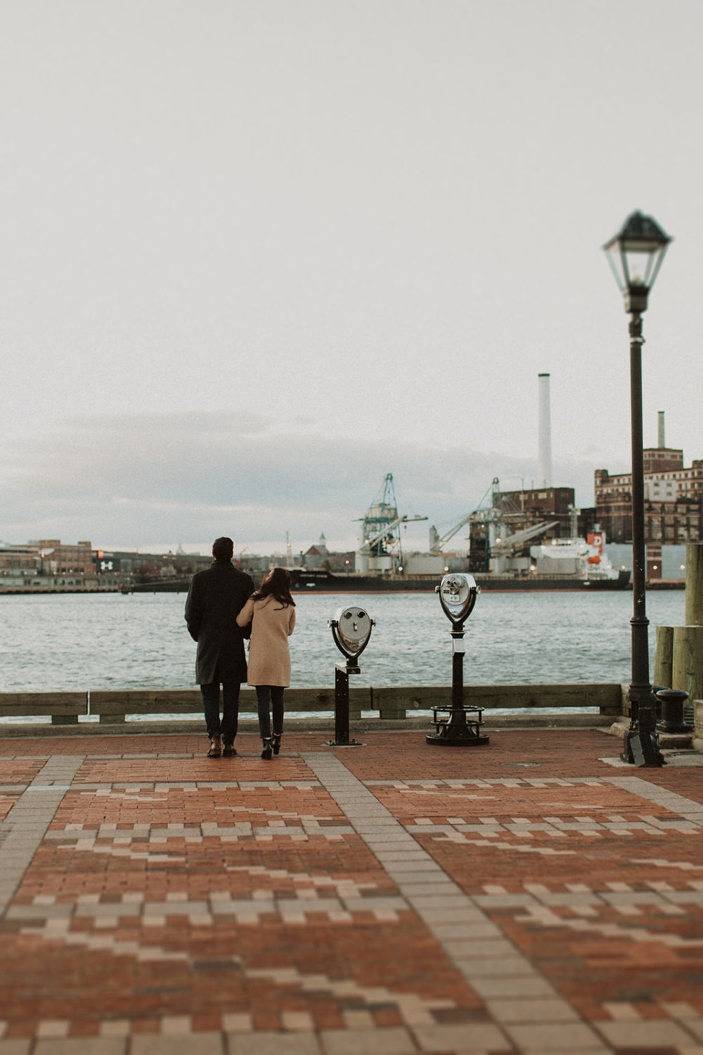 couple embraces at Baltimore waterside winter engagement session