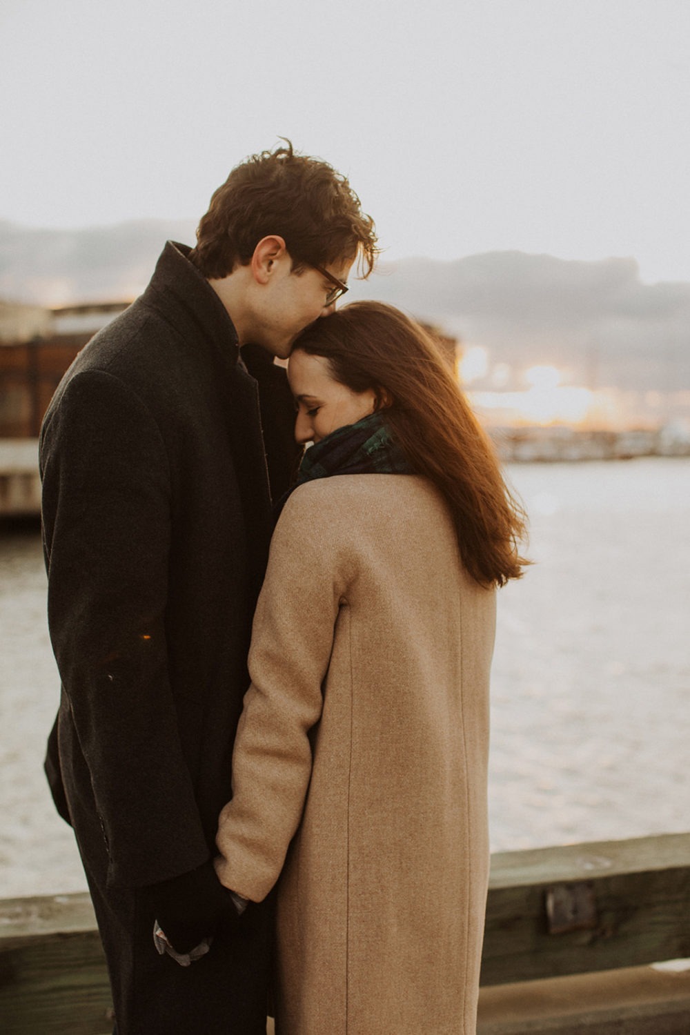 couple embraces at windy winter engagement session