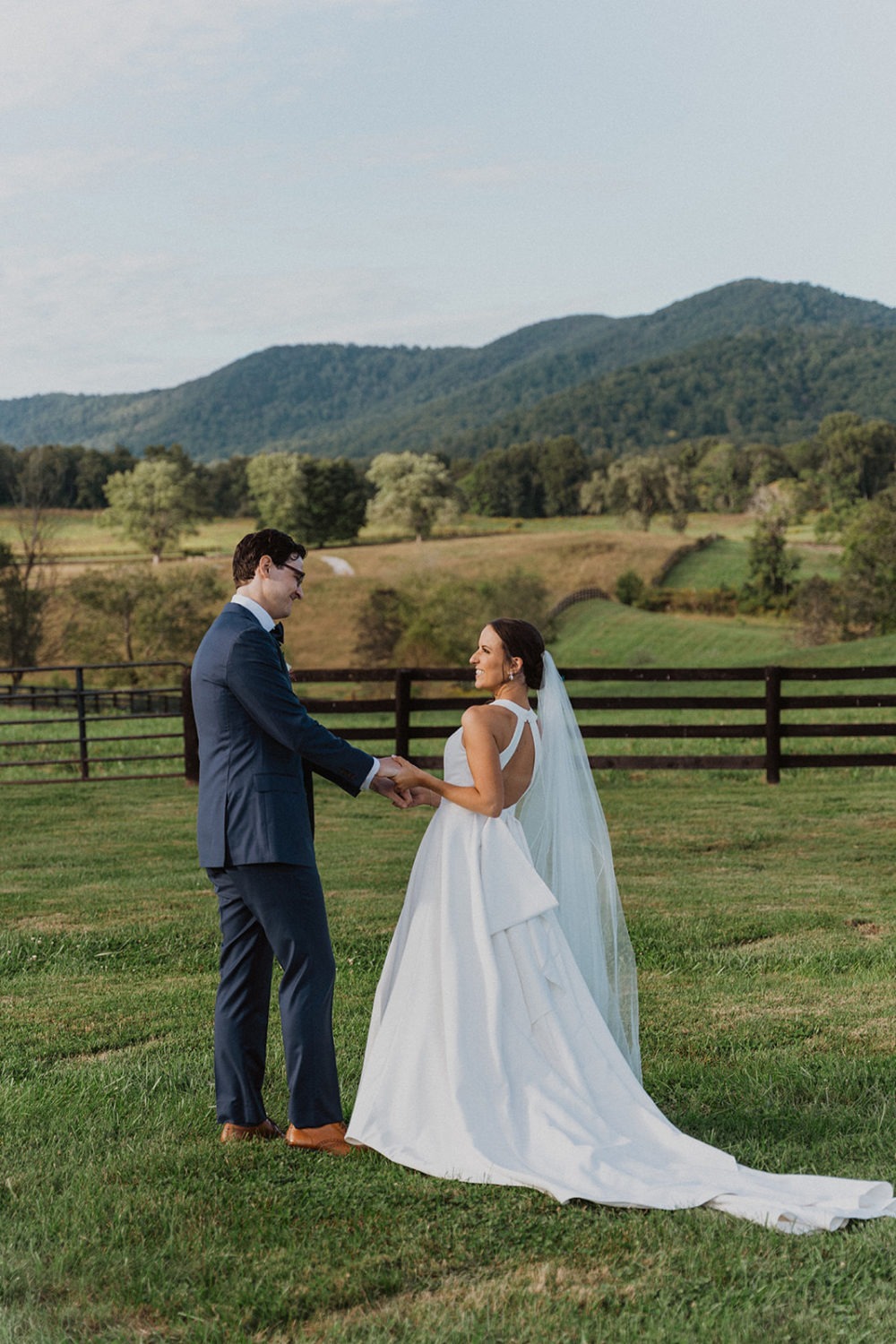 couple holds hands in front of blue ridge mountains at wedding ranch venue