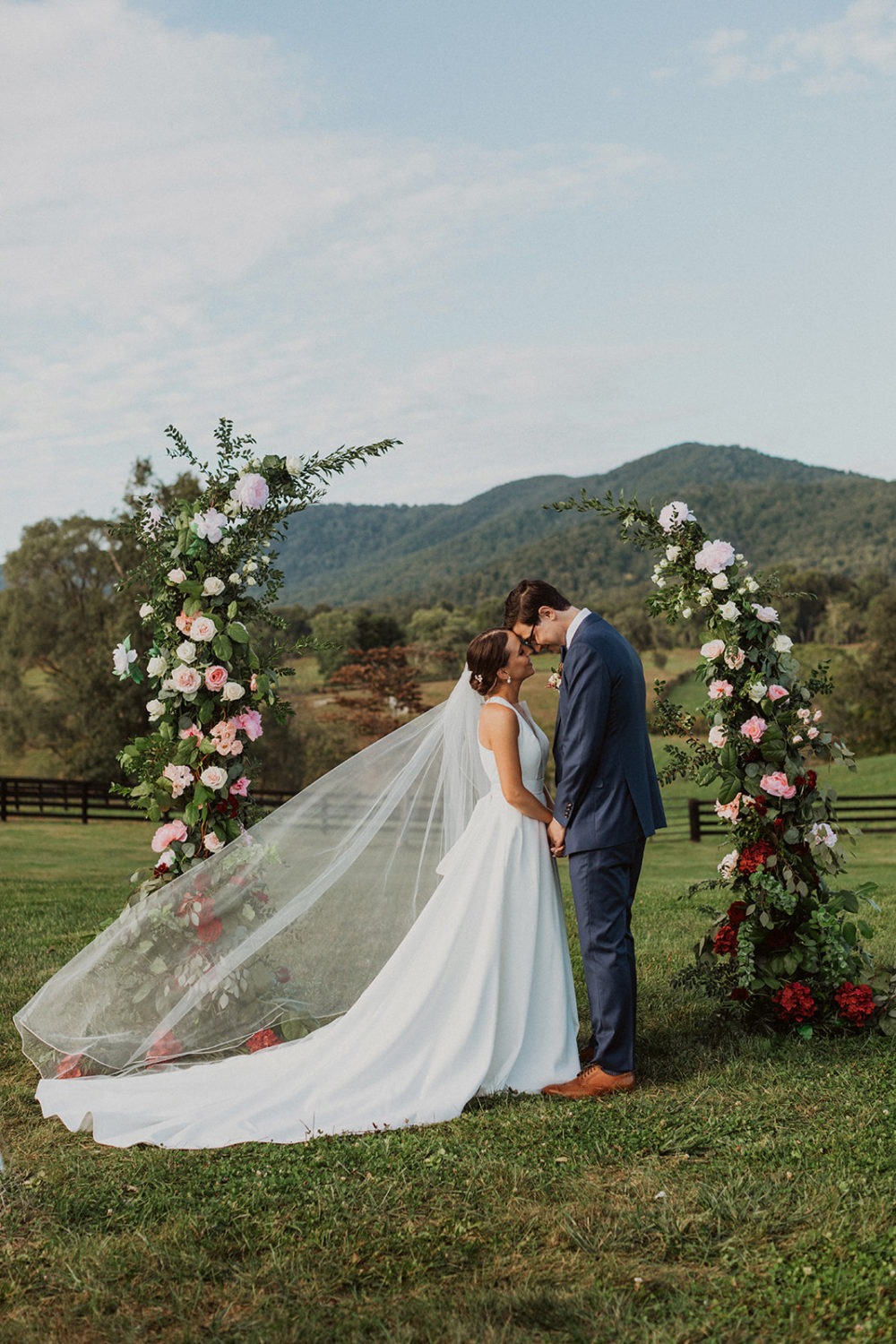 couple holds hands under wedding floral display at mountainside virginia wedding
