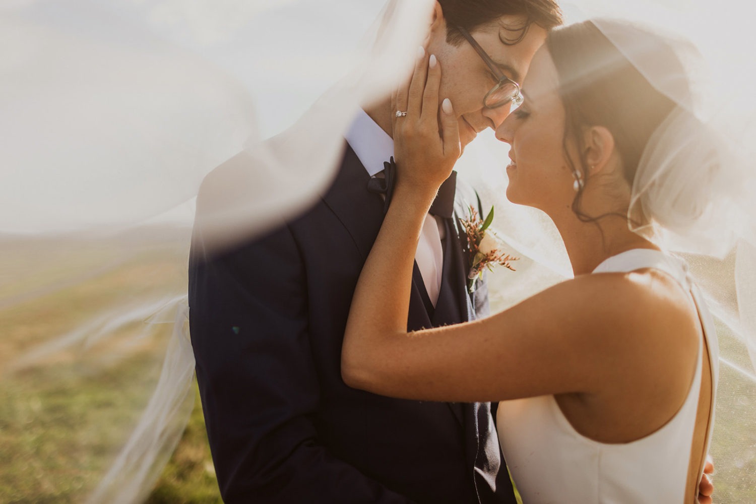 couple kisses underneath veild at wedding ranch venue