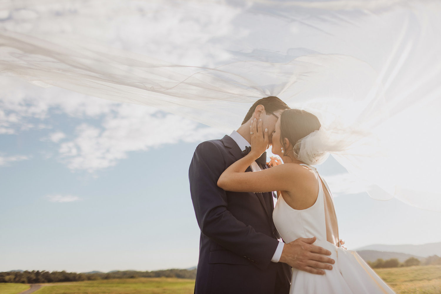 couple kisses under veil during sunset wedding portraits