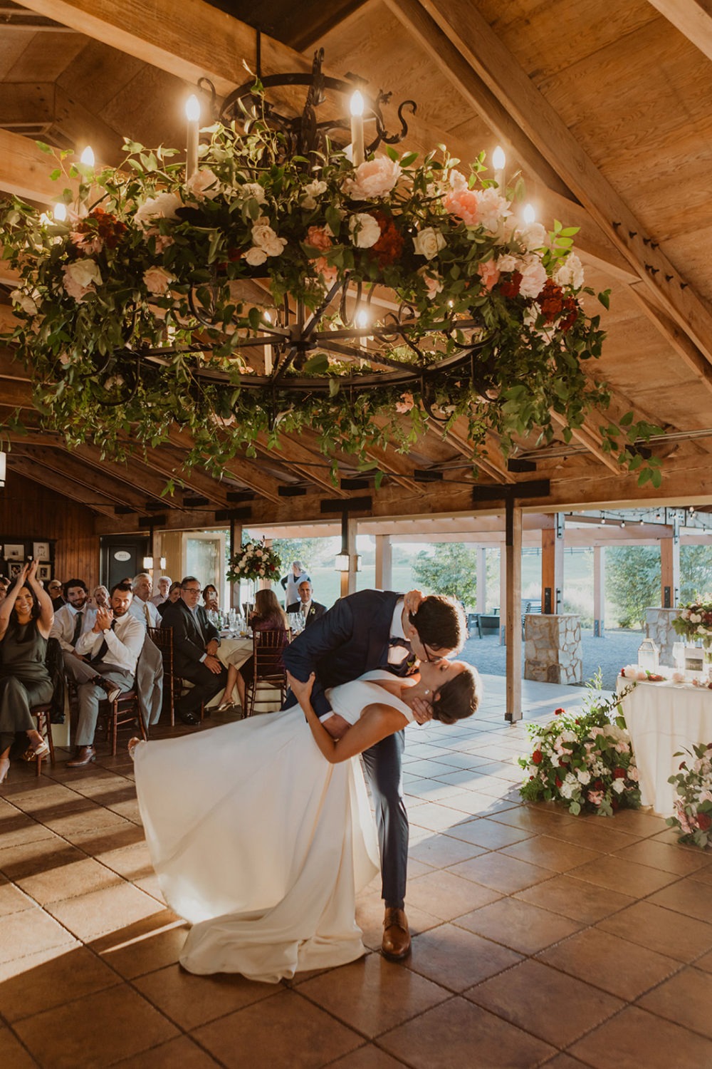 couple kisses under wedding florals lit by candles at wedding ranch venue