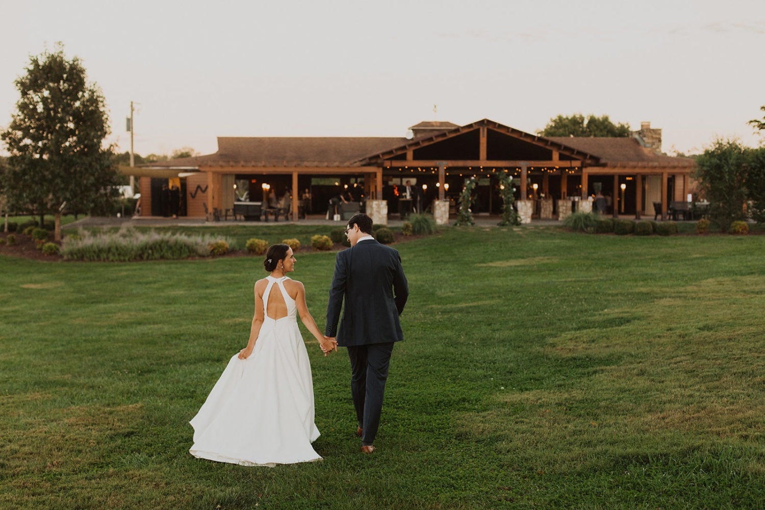 couple walks up to wedding reception space at sunset