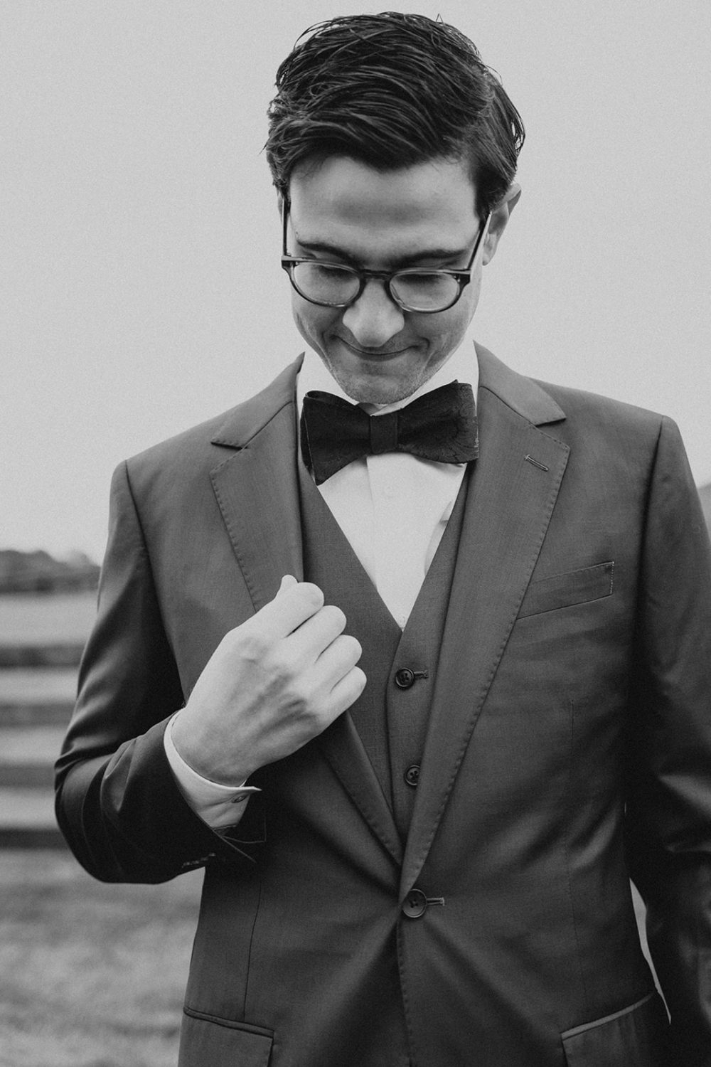 groom holds suit jacket during wedding getting ready