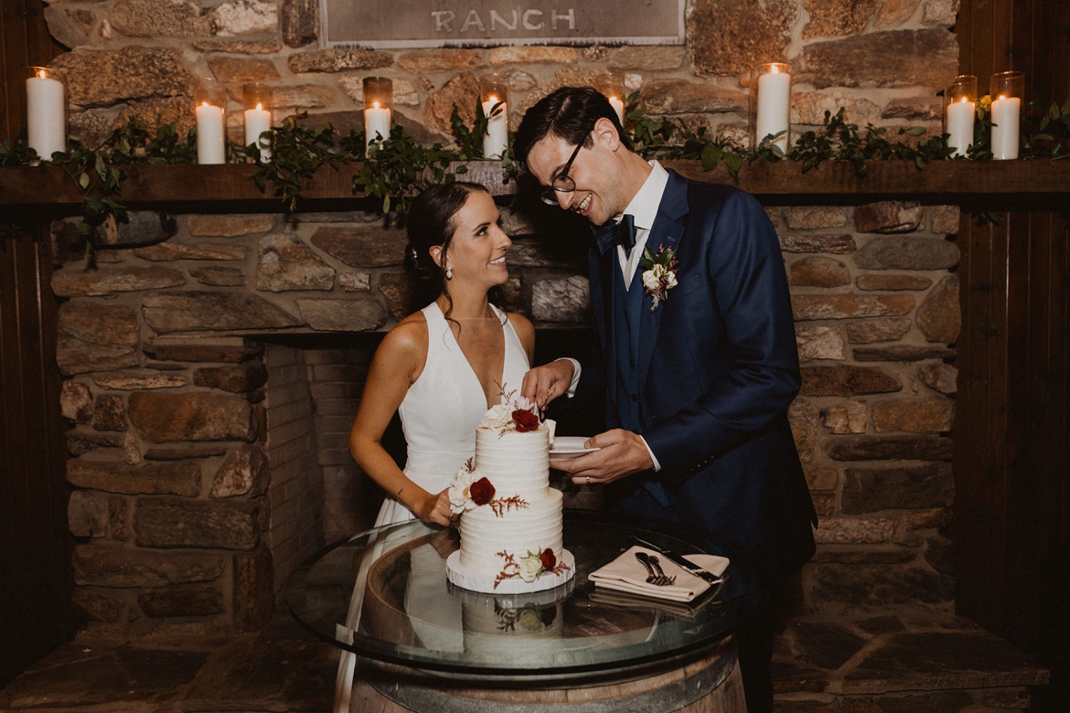 couple cuts cake at farm wedding reception