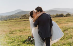 couple embraces kissing at sunset wedding