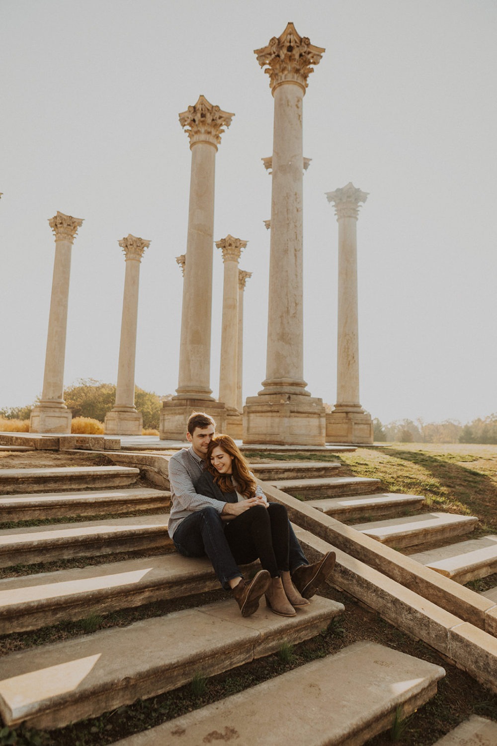 couple sits on steps beneath columns  at National Arboretum DC engagement session