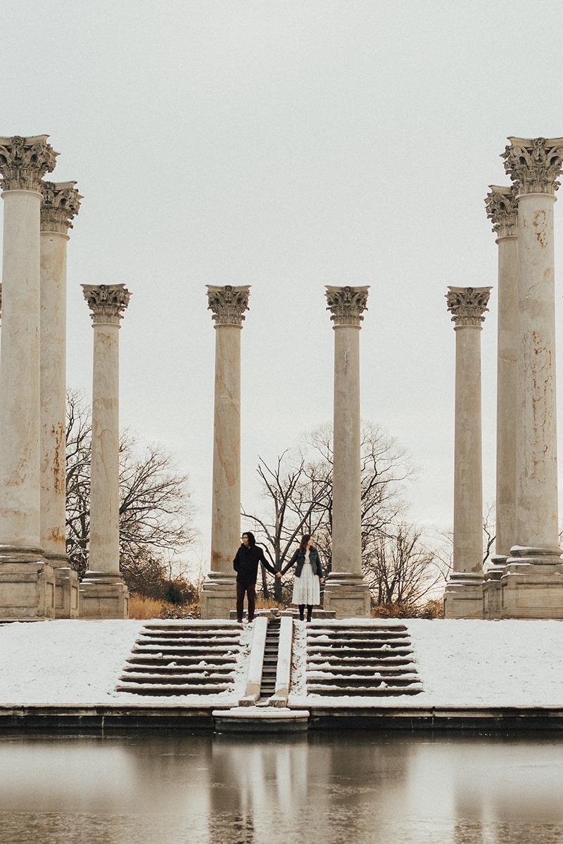 couple holds hands at snow-covered national columns at National Arboretum DC engagement session