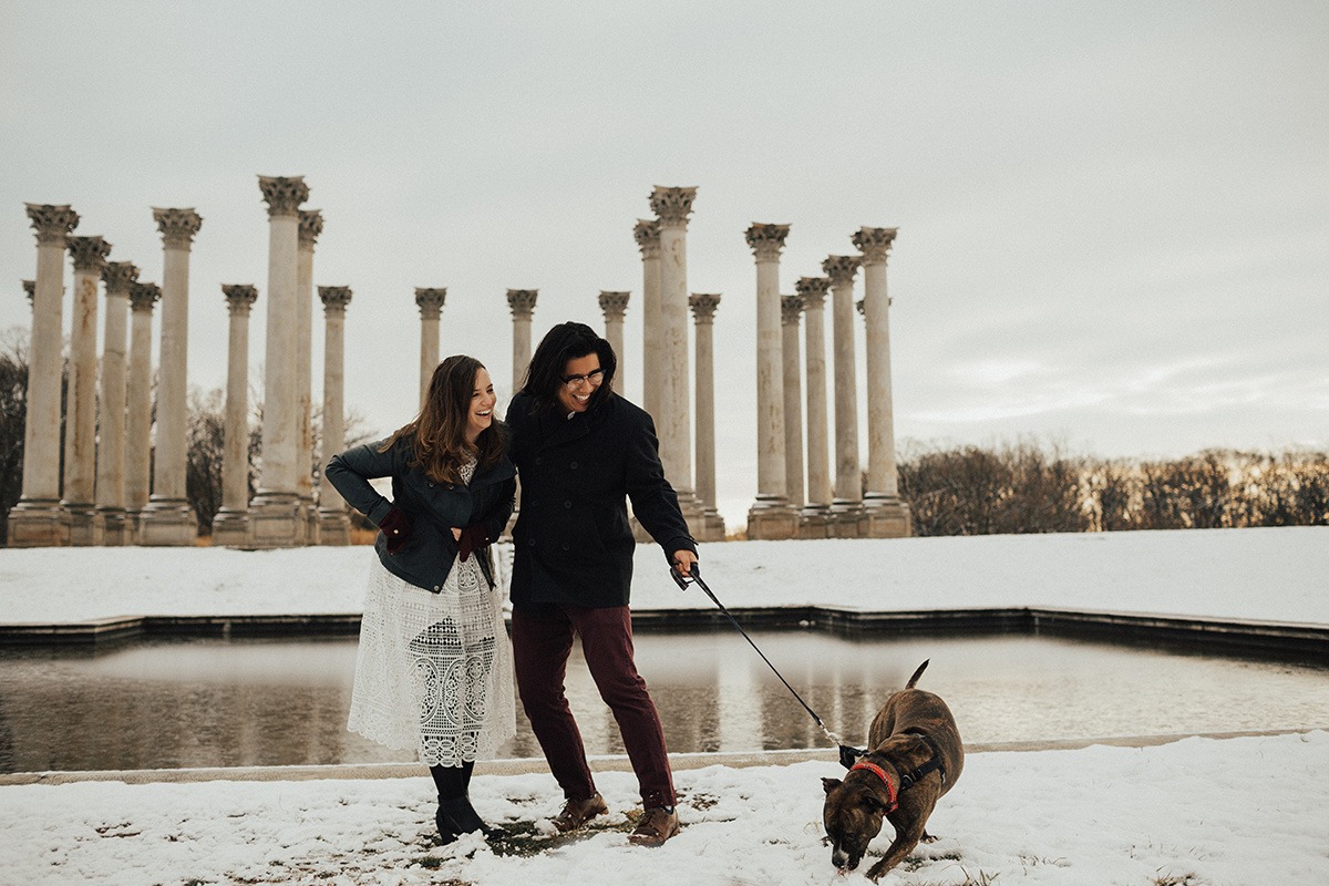 couple walks dog in front of National Columns at National Arboretum winter engagement session