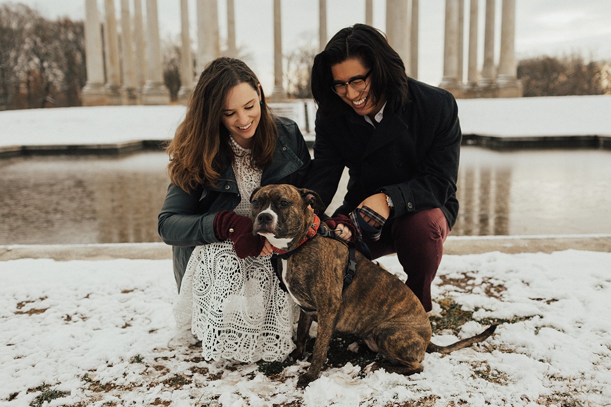 couple pets dog in front of National Columns at National Arboretum winter engagement session