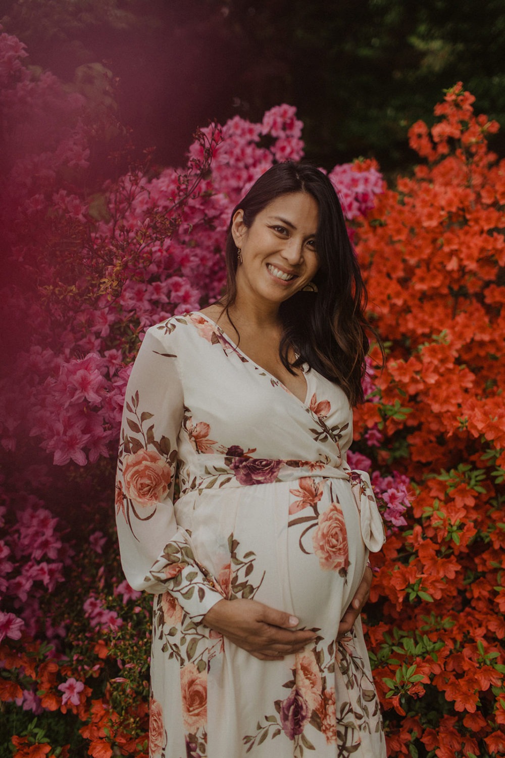 pregnant woman stands in flower garden at maternity session