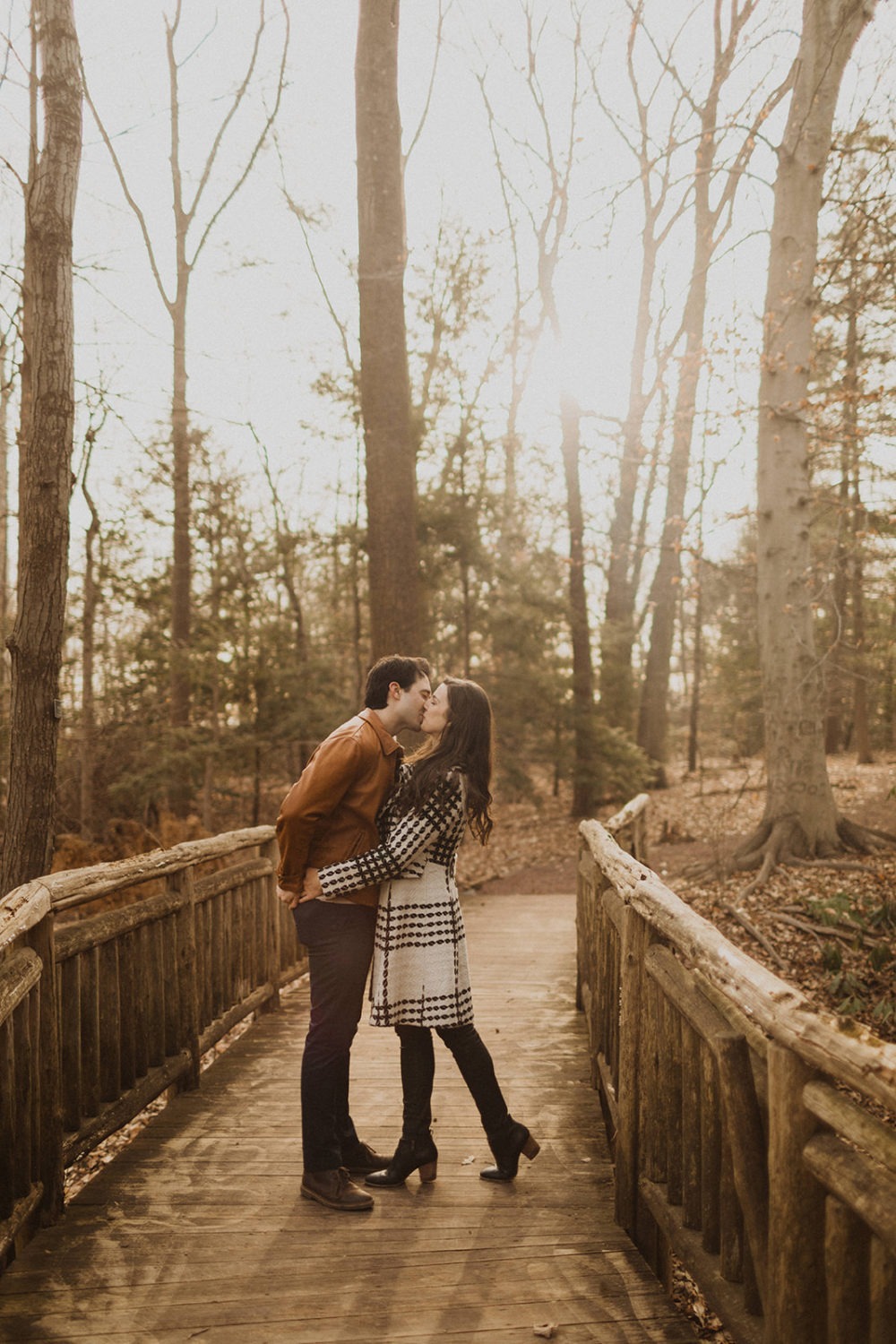 couple kisses on bridge at winter engagement session