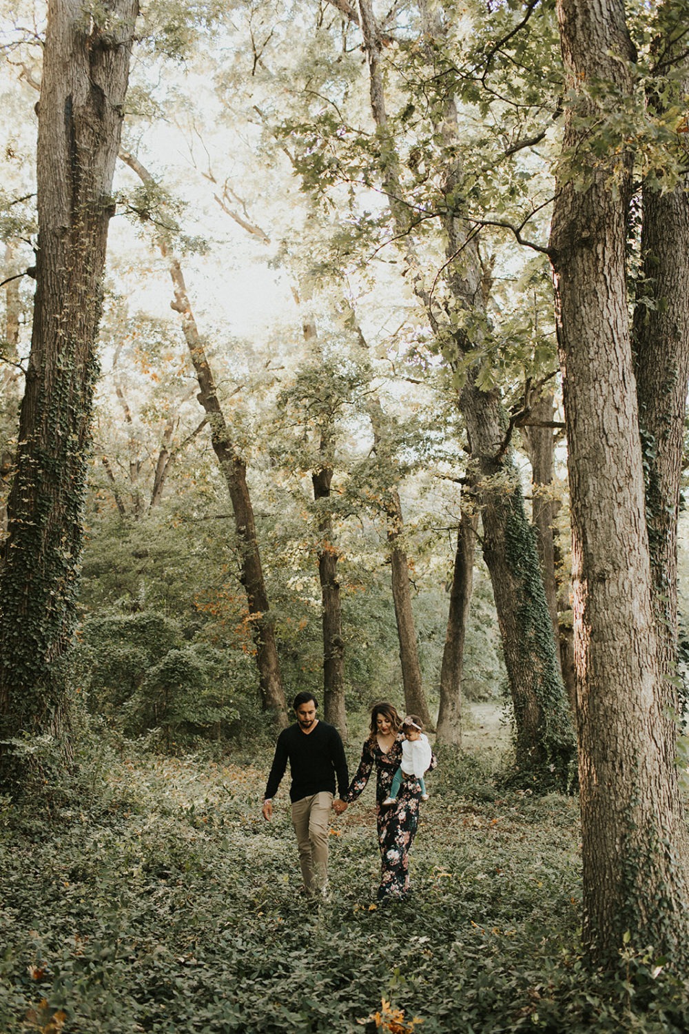 family walks through woods carrying baby at spring family session