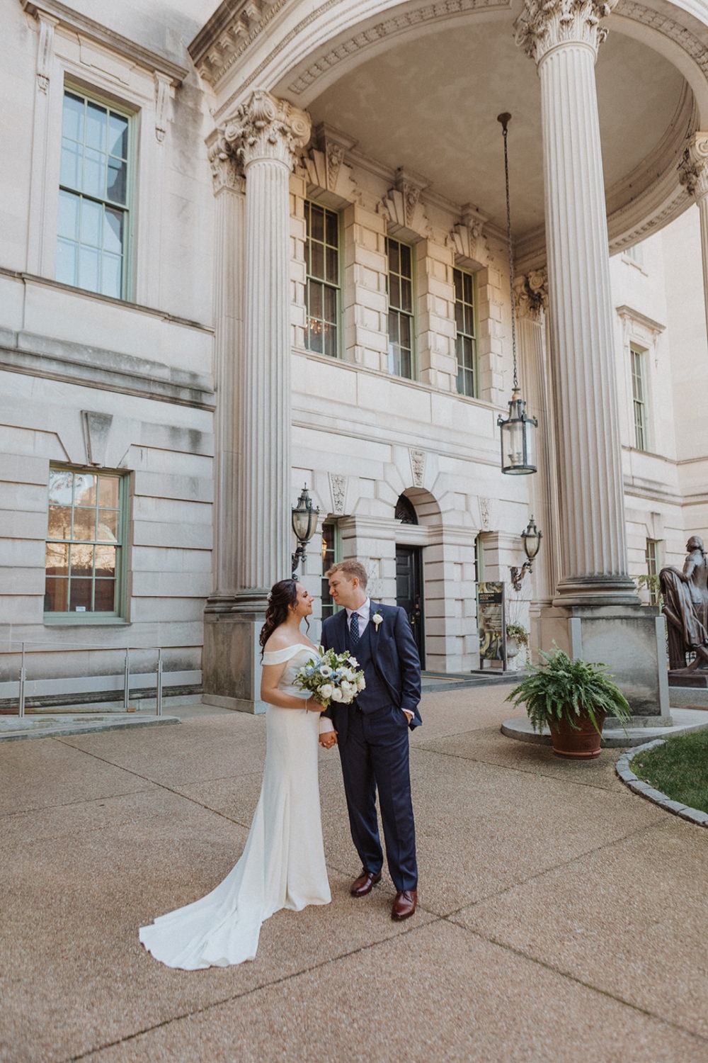 couple stands under columns at DC estate first look