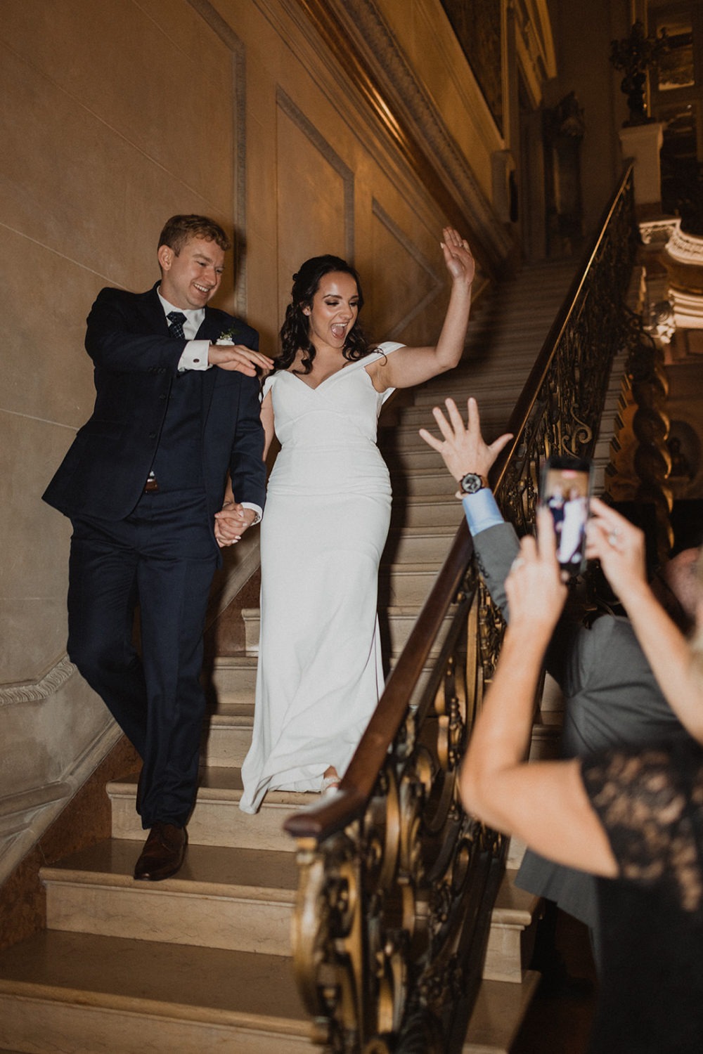 couple walks down grand staircase entering wedding reception