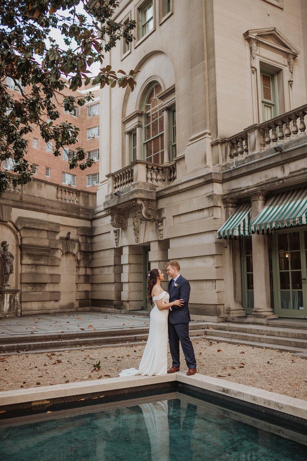 couple stands in courtyard by reflection pool at mansion wedding venue
