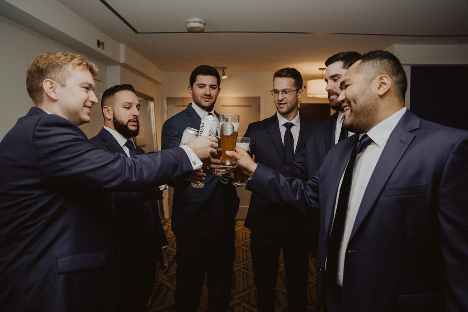 groomsmen cheers with beers in DC hotel for urban wedding