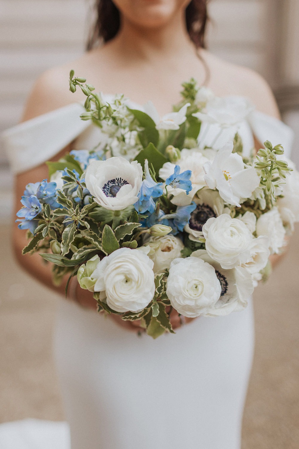 bride holds white and blue wedding bouquet