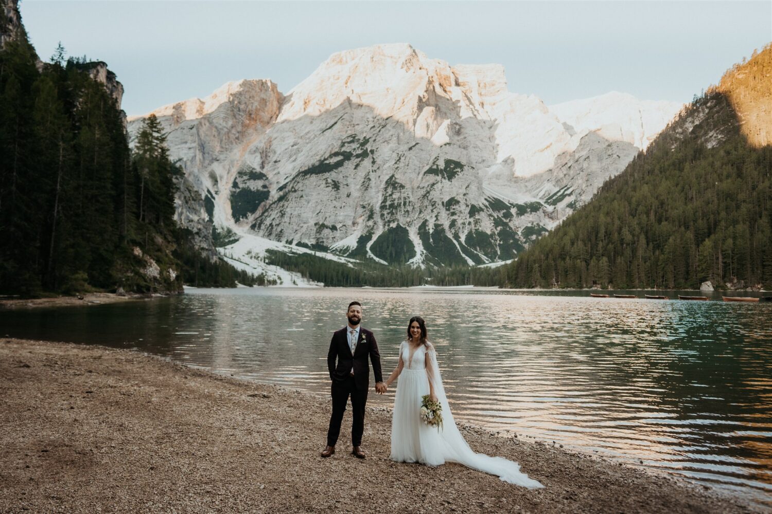 couple stands beside lake at their Italian Dolomites elopement