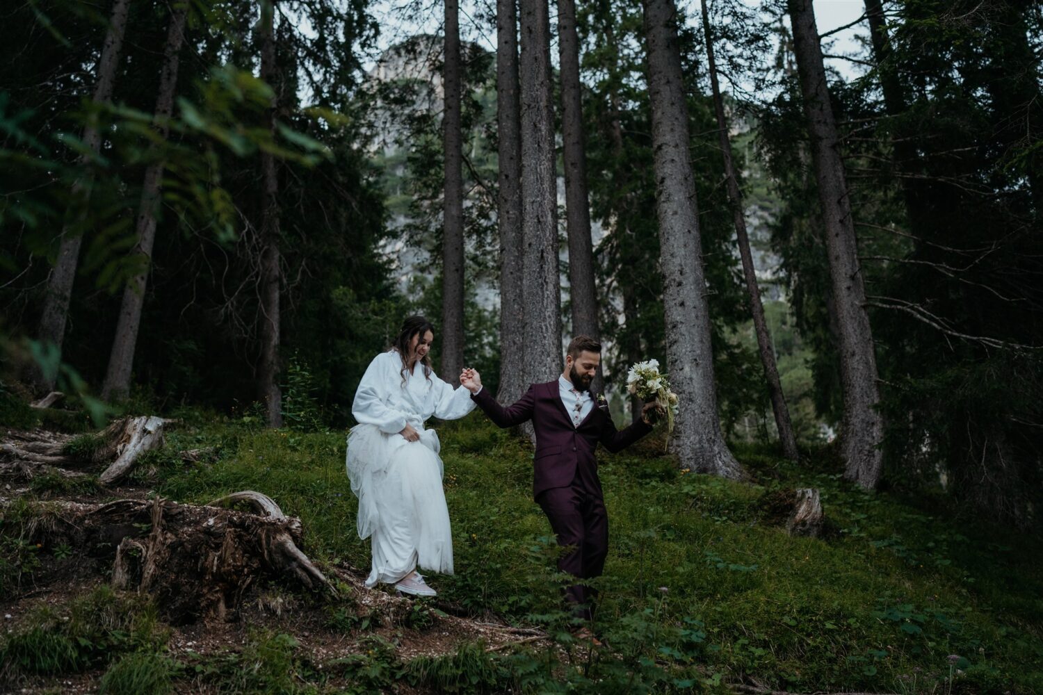 couple walks through woods for Italian Dolomites first look