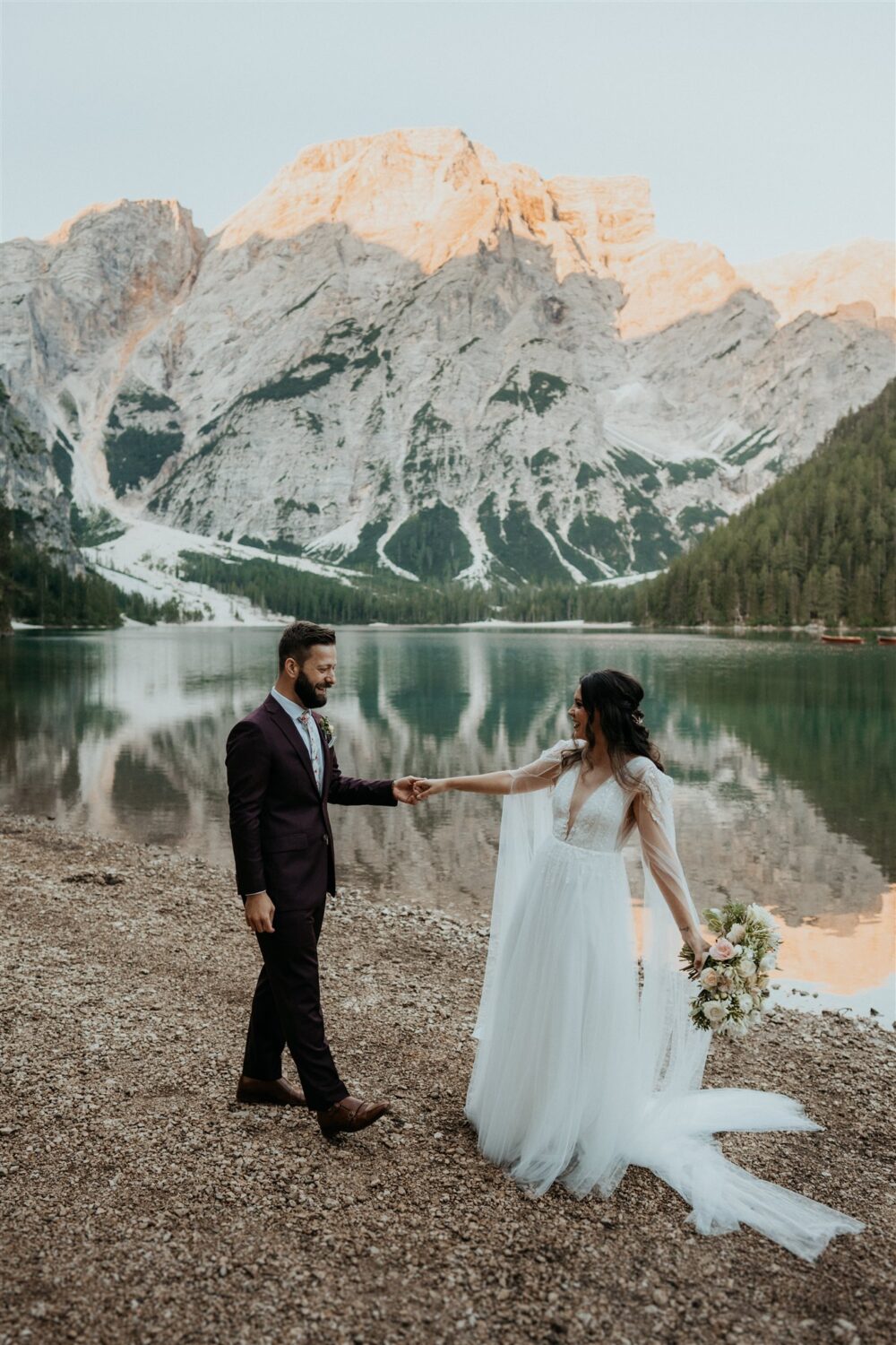 couple holds hands lakeside at the Dolomites Italy elopement 