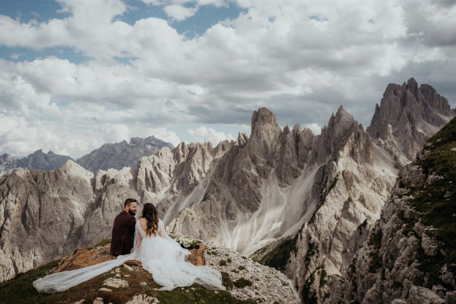 couple sits on mountaintop and eats picnic at Italy elopement