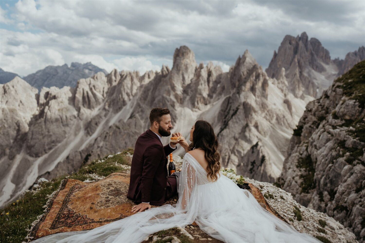 couple eats sandwich at mountaintop picnic on the Italian Dolomites