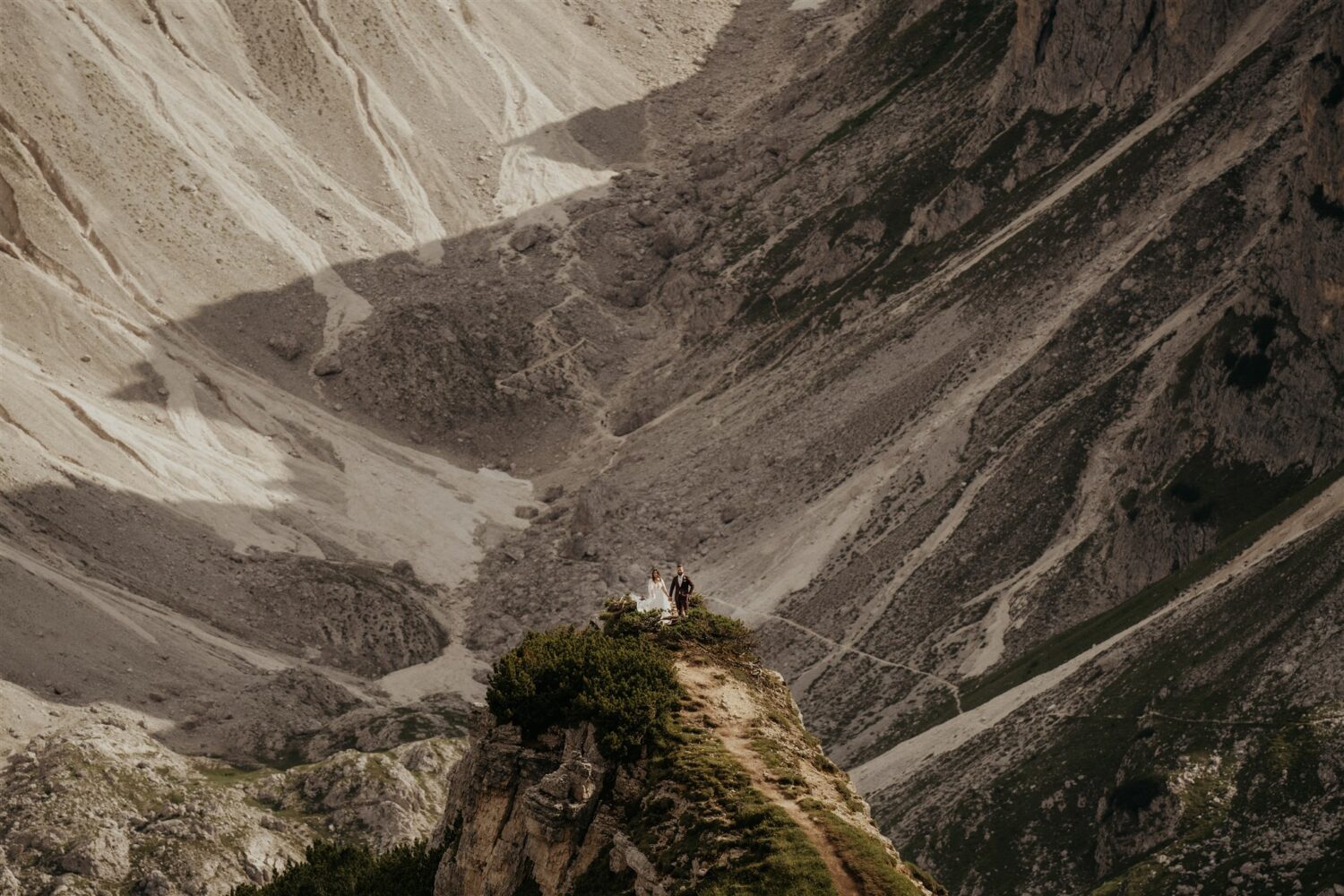 couple stands on cliff edge below the Dolomites at their Italy elopement