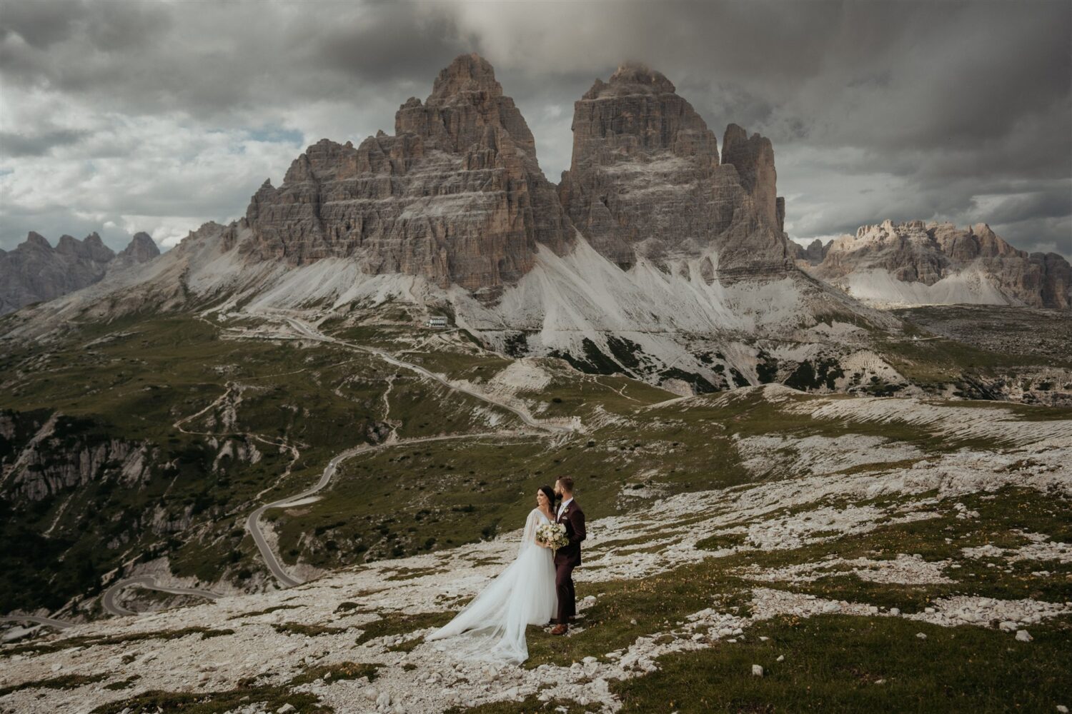 couple stands under cloud-covered mountains at the Italian Dolomites