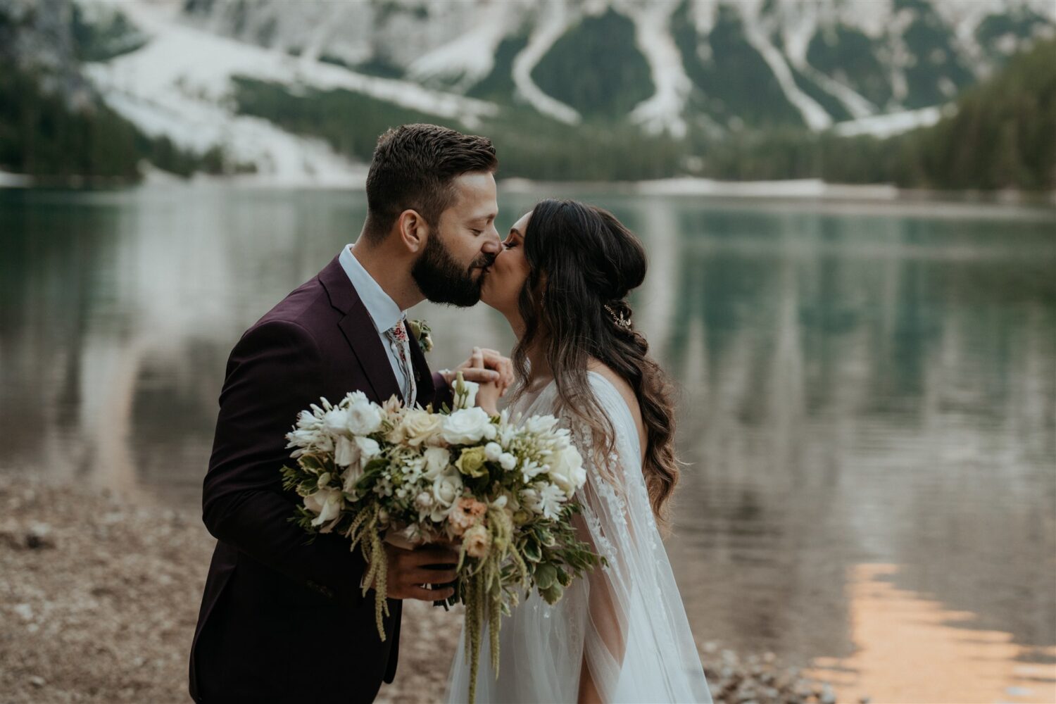 couple kisses by Italian mountainside lake