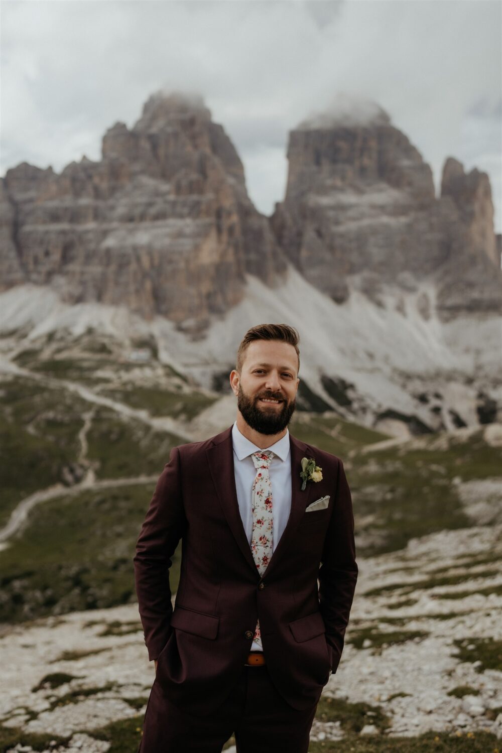 groom smiles standing in front of the Italian Dolomites