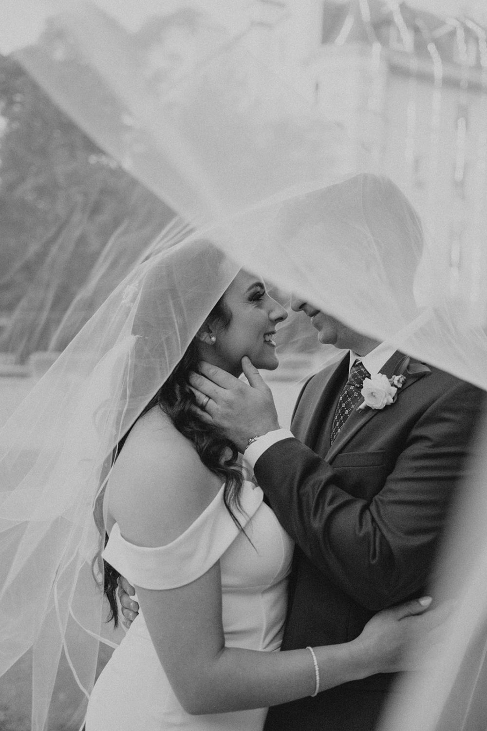 couple embraces under flowing wedding dress veil