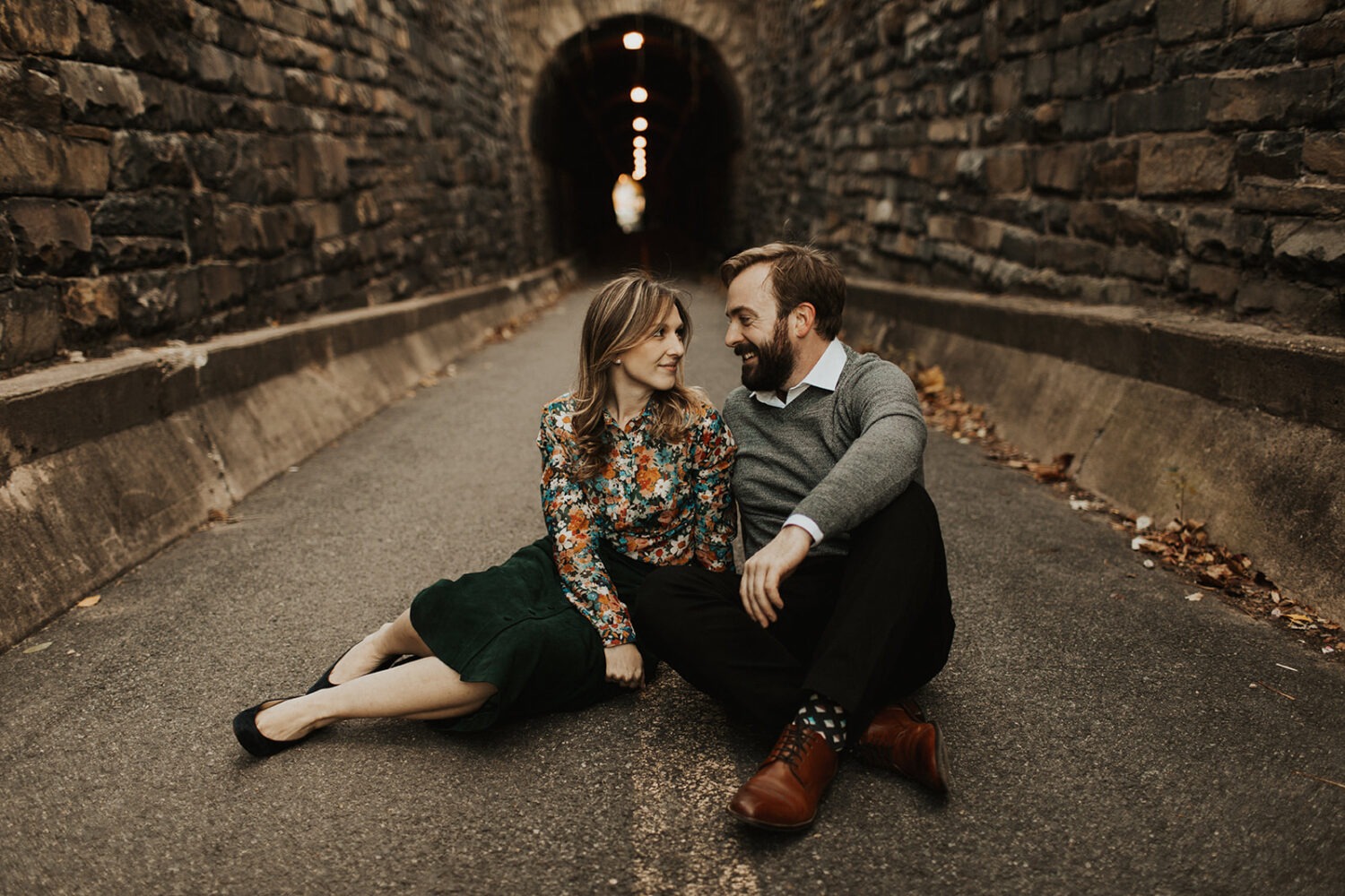 couple sits on ground in front of tunnel